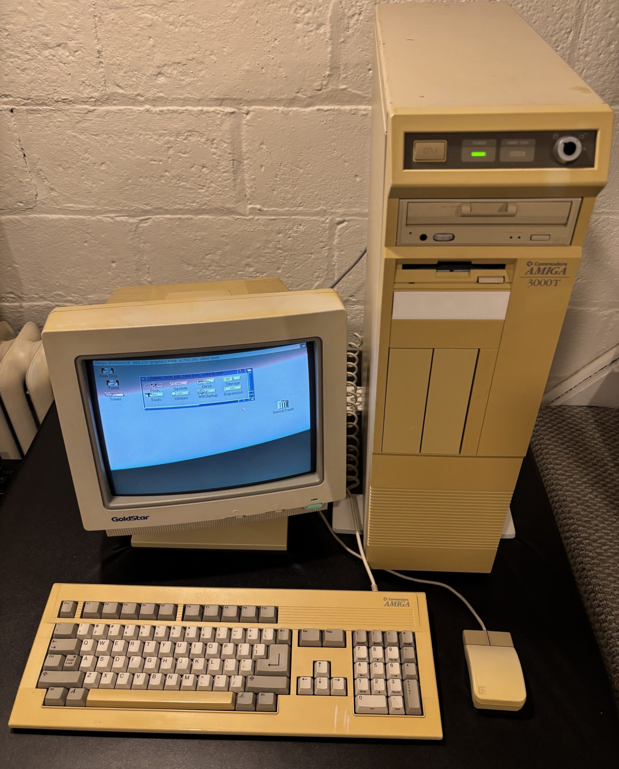 An image of a Commodore Amiga 3000T in upright position on the right, a small VGA monitor on the left, with a keyboard and mouse visible in the front.